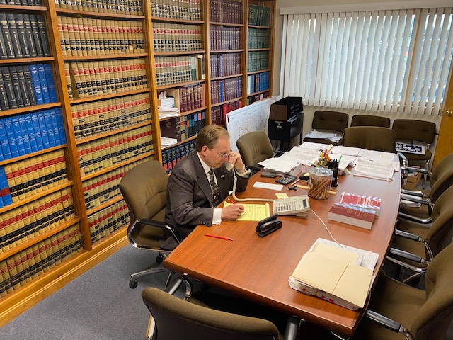 Attorney Jay McMahon working in his professional Buzzards Bay law office conference room with extensive legal library